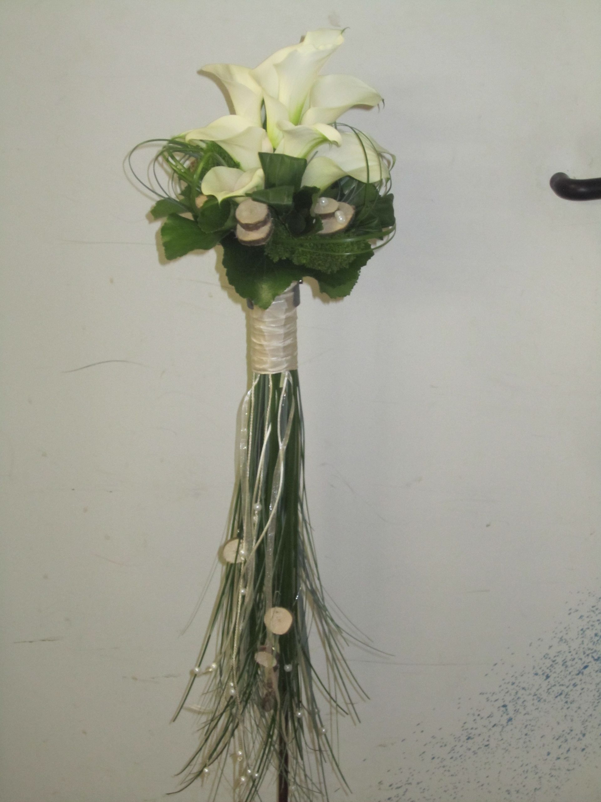 Calla-Lilien-Bouquet, weiße Lilien, grünes Laub, umwickelter Griff, herabhängendes Grün, Holzakzente.