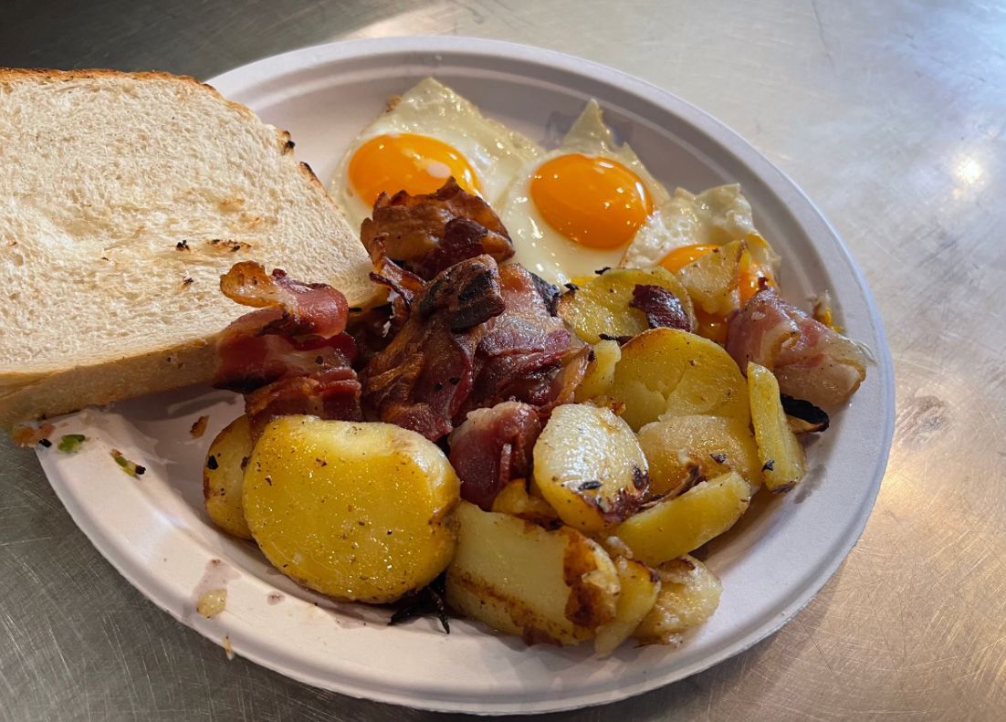 Breakfast plate with fried eggs, bacon, potatoes, and toast.