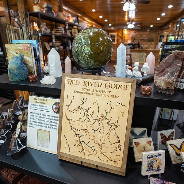 A retail display featuring a wood-burned map of Red River Gorge, crystals, and butterfly art.