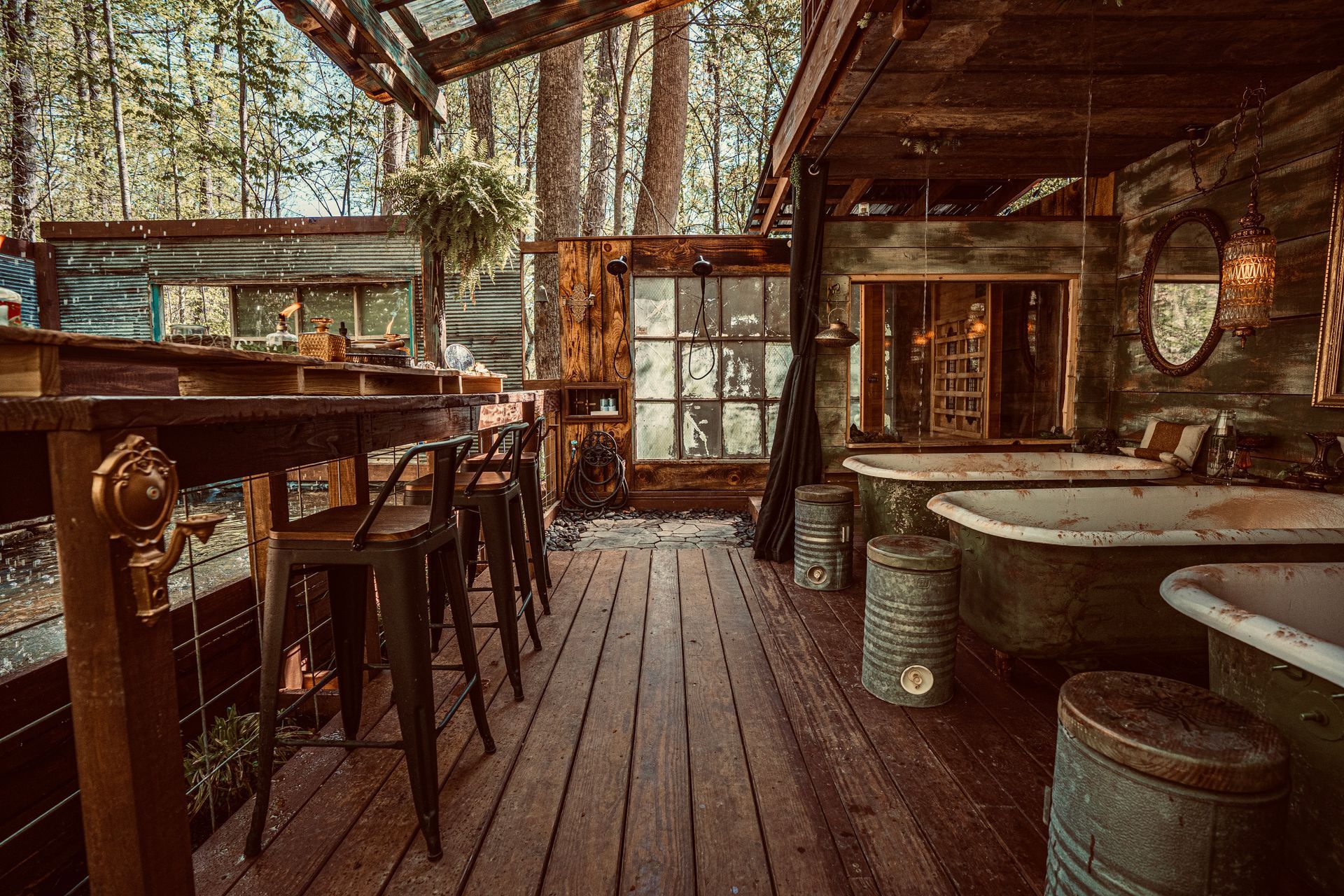 Outdoor bar and spa area with bathtubs. Wooden deck and bar, rustic decor, forest backdrop.