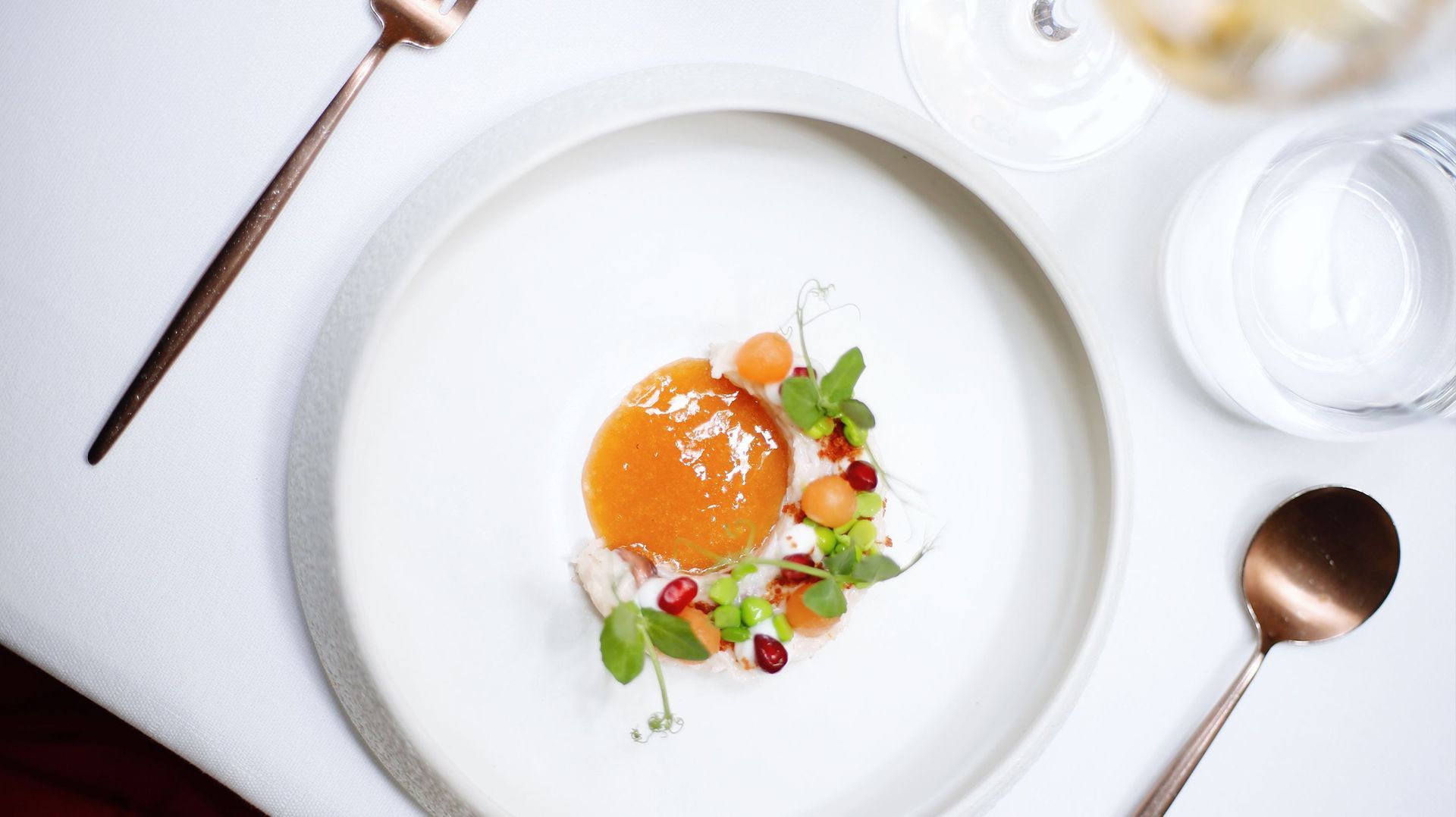 Minimalistisch op een wit gedekte tafel met een dessert van sinaasappelsaus, bessen en kruiden.
