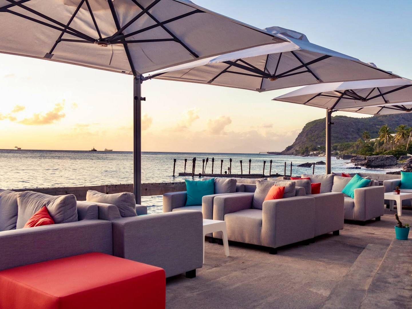 Terras met uitzicht op de zonsondergang, comfortabele zitgelegenheid, parasols en uitzicht op de oceaan.