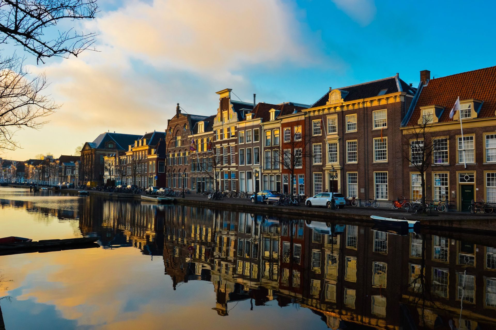 Hotel met een zonnige binnenplaats, een turquoise zwembad, gele balkons en roze bloeiende klimplanten.