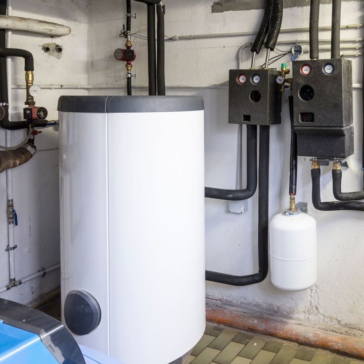 Un calentador de agua blanco en una habitación con tuberías.