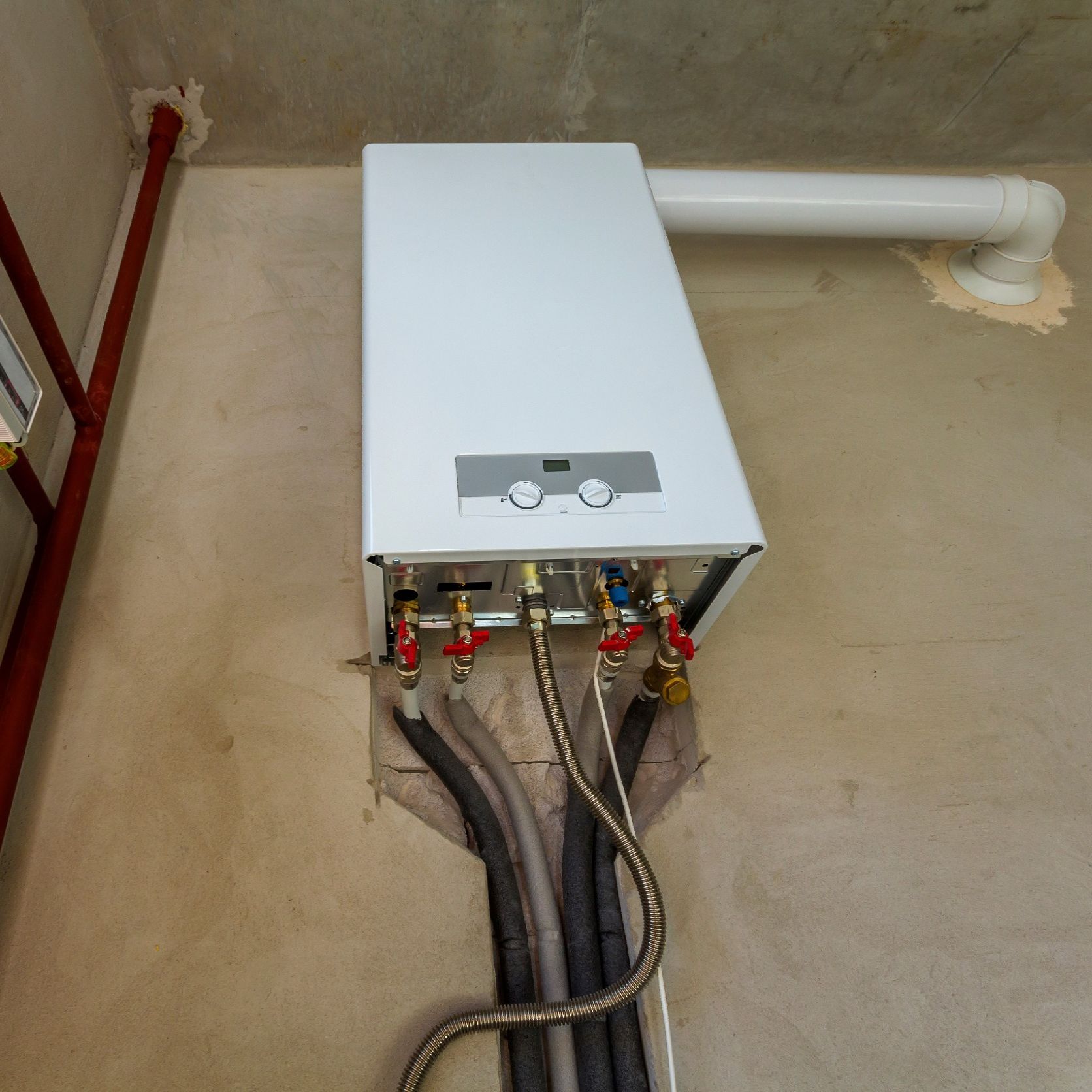 Un calentador de agua blanco en una habitación con tuberías.