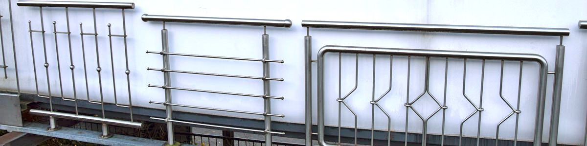 Eine Reihe von Edelstahlgeländern vor einer weißen Wand