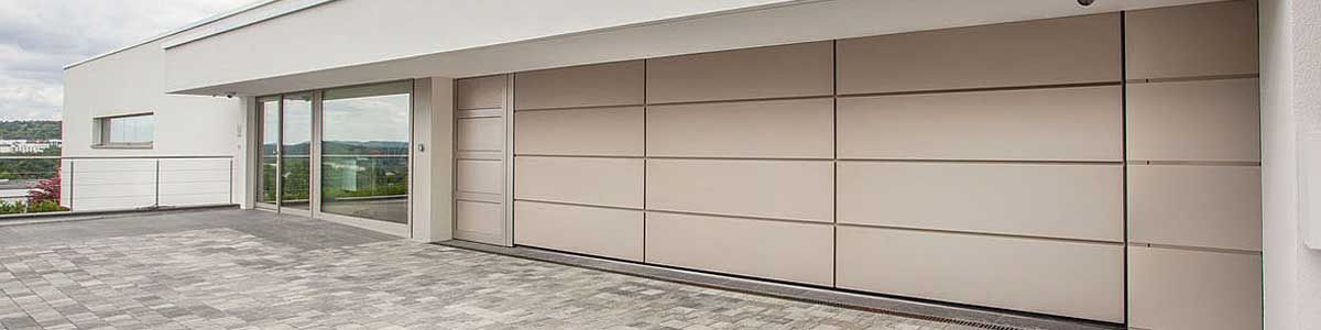 Ein weißes Gebäude mit einem großen Garagentor und vielen Fenstern.