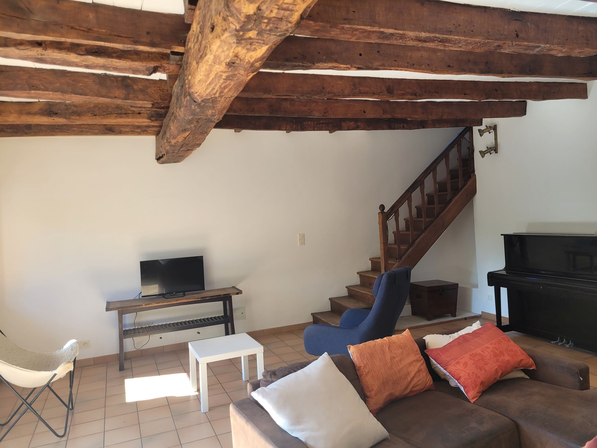 Salon avec poutres apparentes et escalier en bois