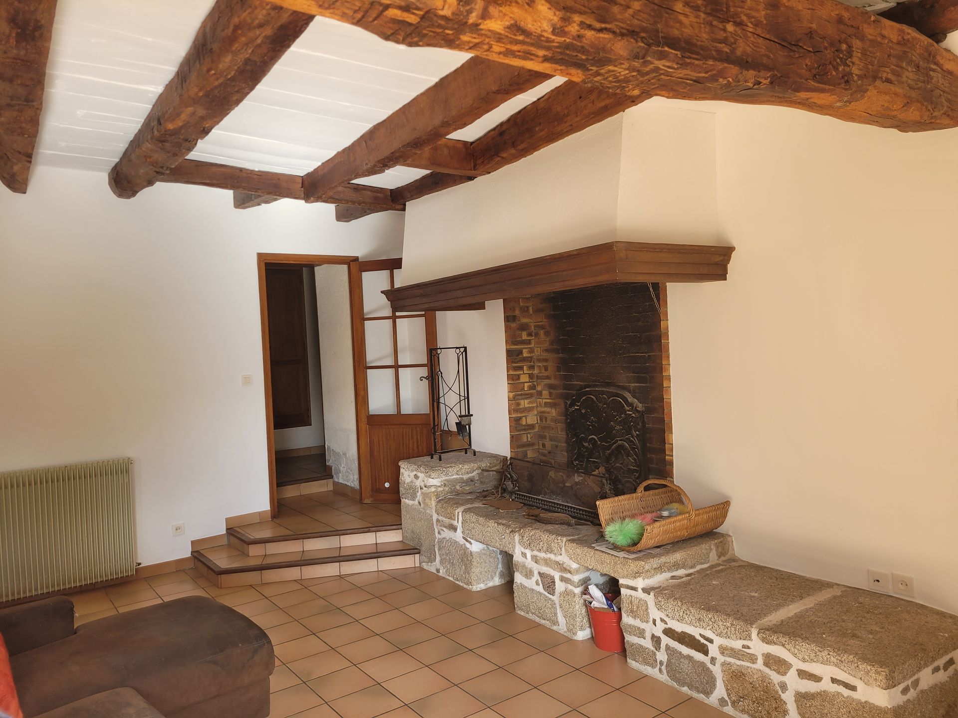 Salon repeint avec poutres apparentes et cheminée