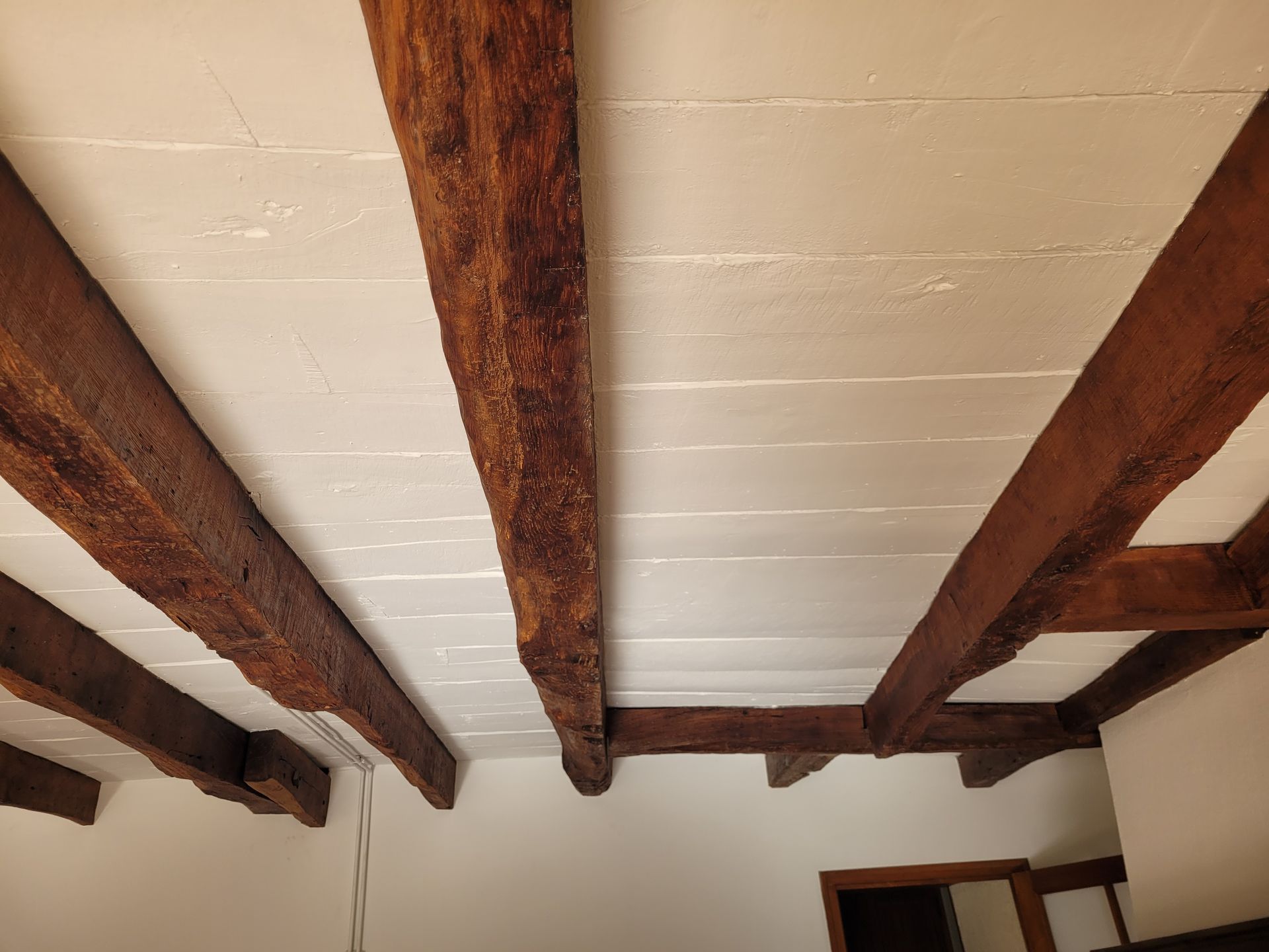 Détail sur les finitions d’un plafond en bois et poutres apparentes
