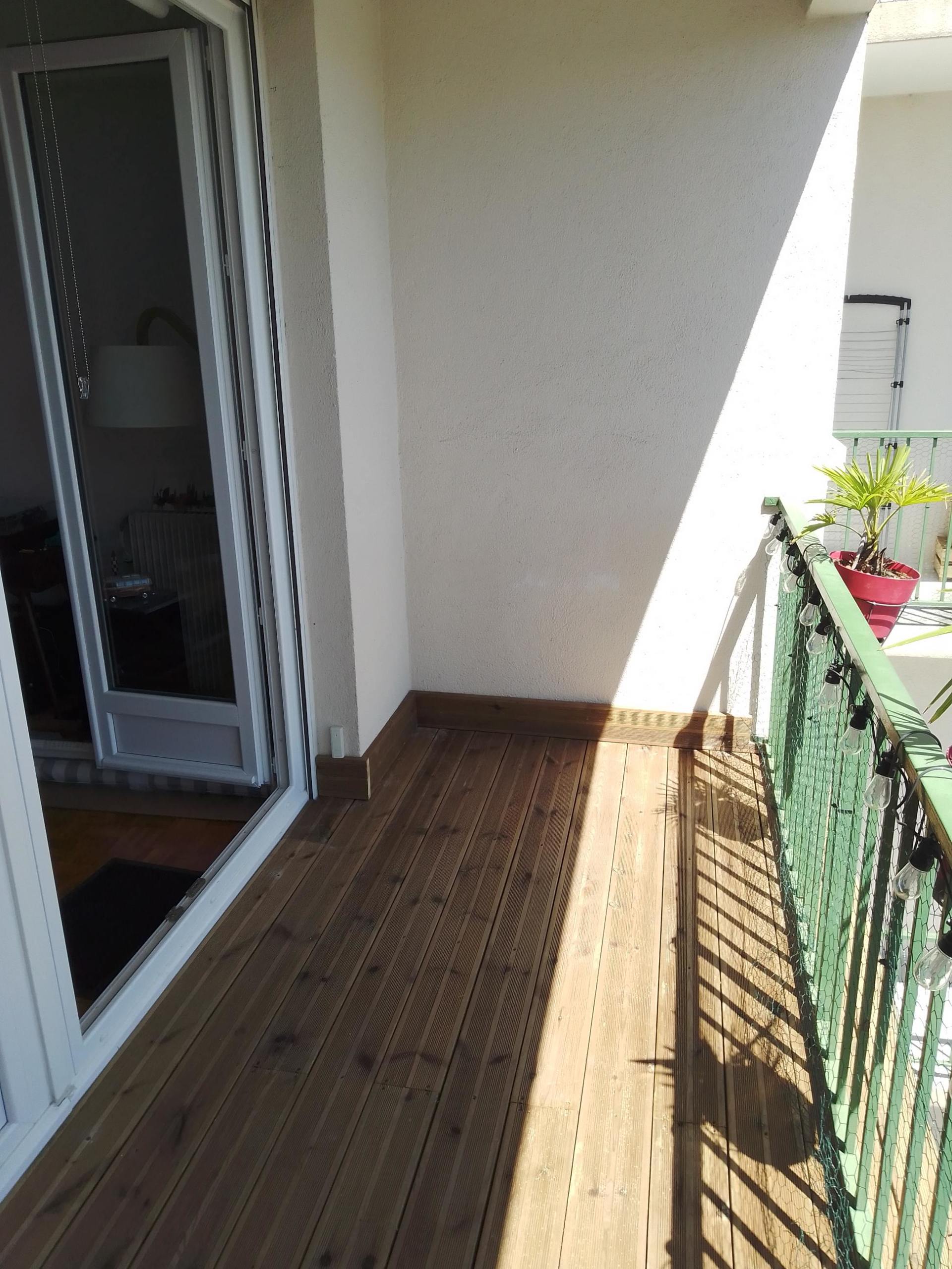 Balcon avec un sol en planche de bois avec une clôture verte