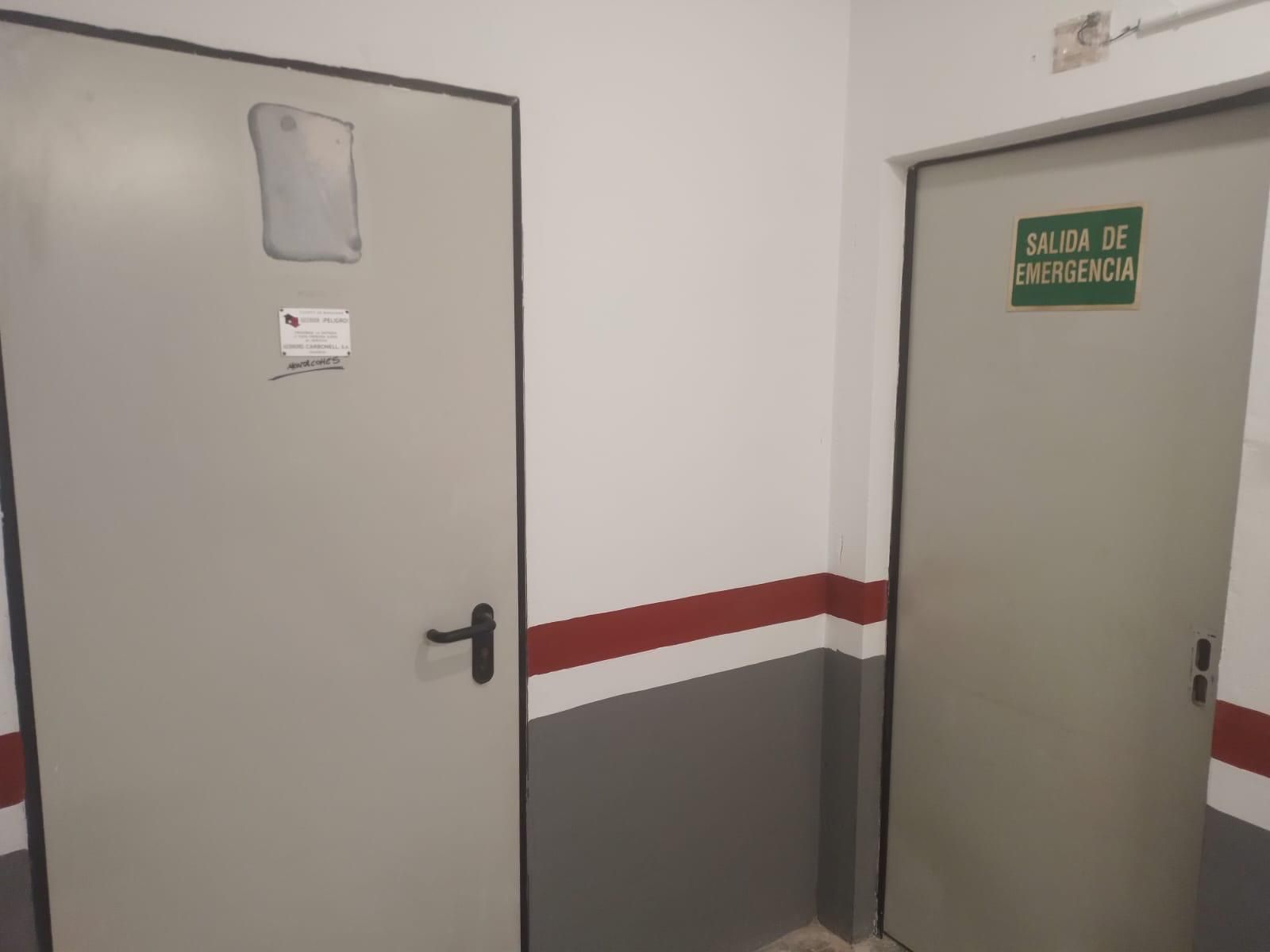 Dos puertas grises en un pasillo. Una tiene un letrero y la otra dice