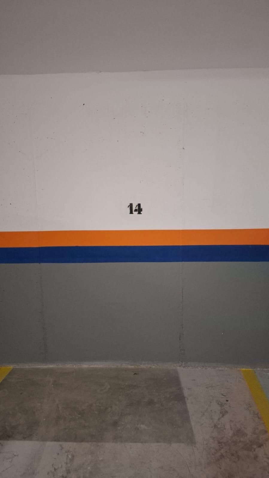 Pared de garaje con el número 14. Rayas naranjas y azules con paneles grises.