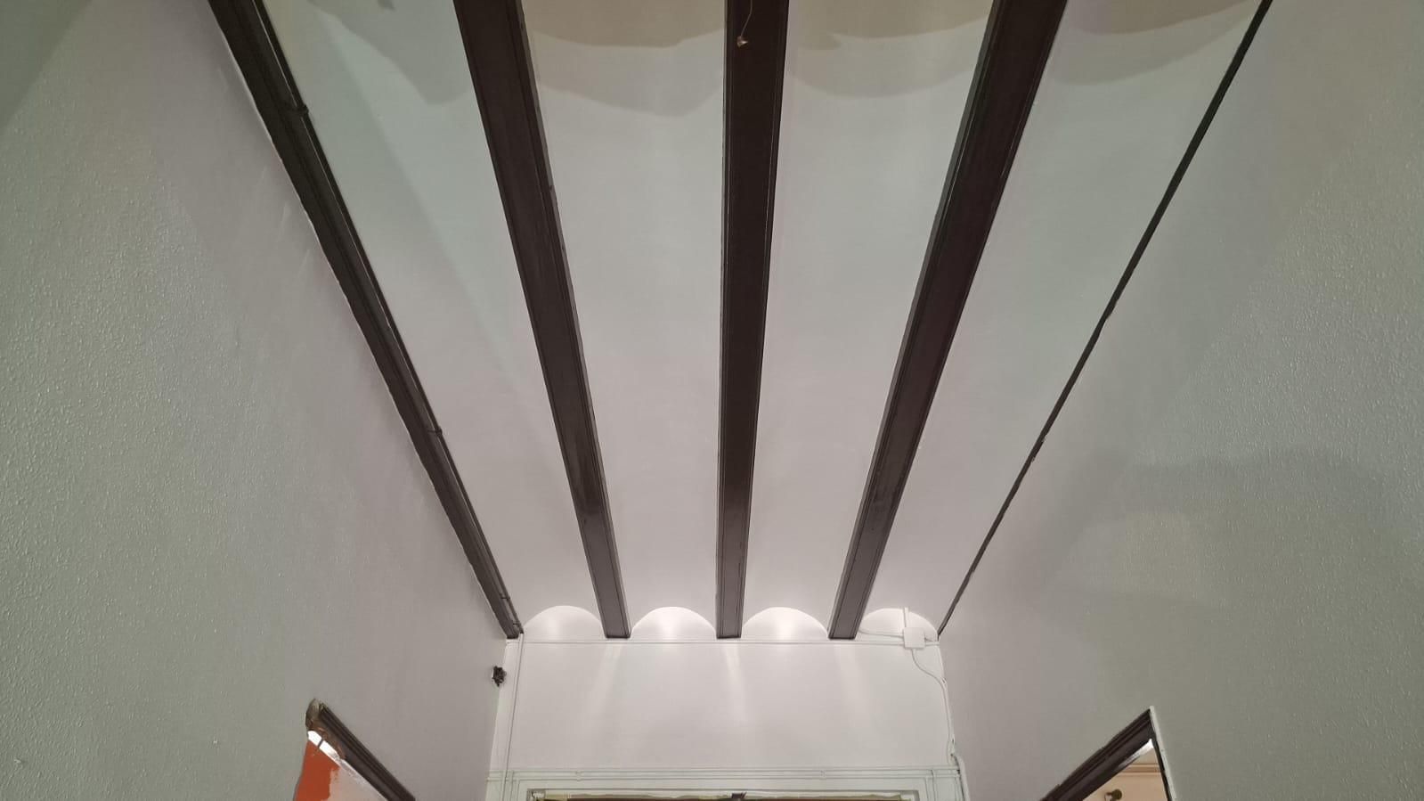Techo blanco con vigas de color marrón oscuro.