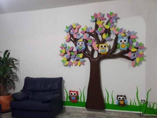 Una habitación con una silla y un árbol con búhos.