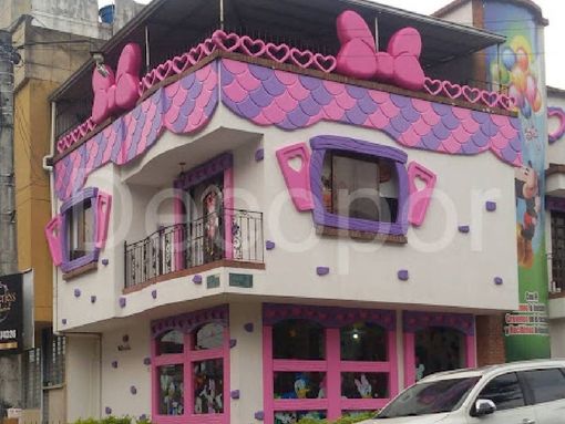 Un edificio rosa y morado con un coche aparcado delante.