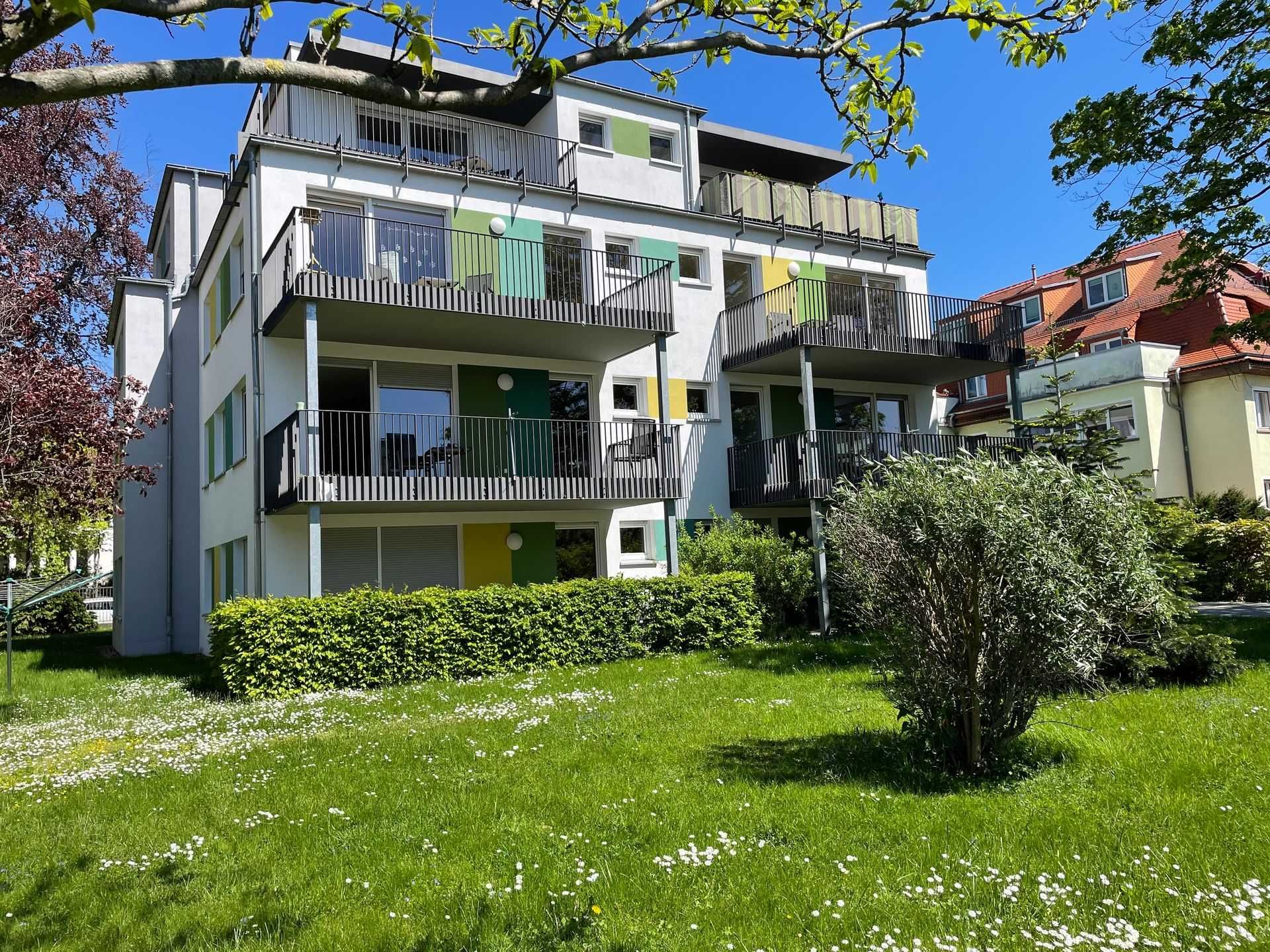 Kommode vor einer blauen Wand mit abstraktem Gemälde, Lampe und Tür. Holzboden.