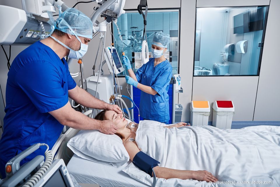 Ärzte versorgen einen Patienten im Krankenhausbett mit medizinischen Geräten.