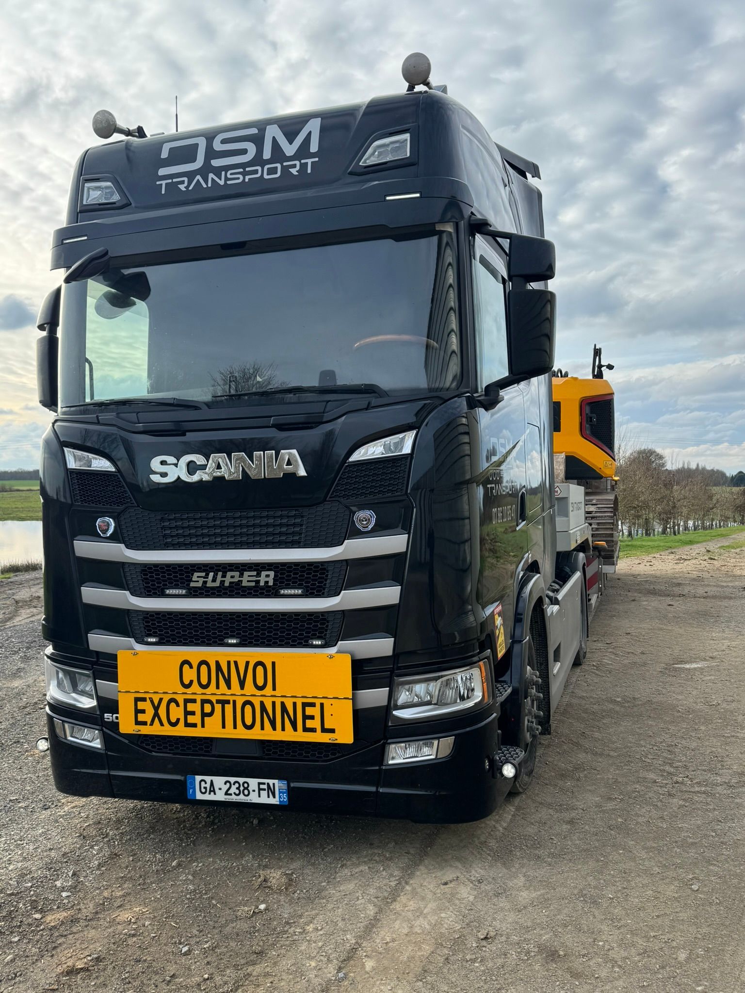 Camion Scania noir sur une route de campagne, vu de face.