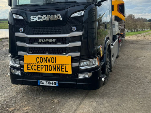 Camion noir en bord de route, avec un écriteau Convoi Exceptionnel.