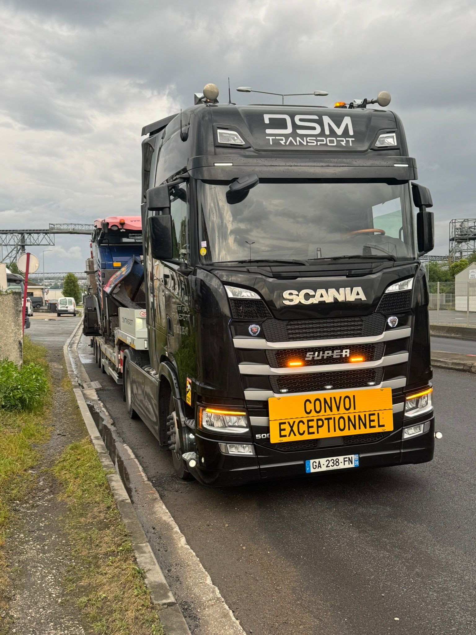 Un camion noir DSM Transport, avec un écriteau Convoi Exceptionnel.
