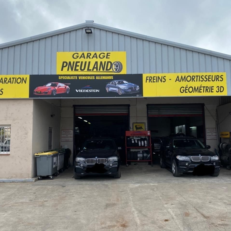 Garage Pneuland avec deux SUV à l'intérieur. Signalétique : pneus, freins et amortisseurs.
