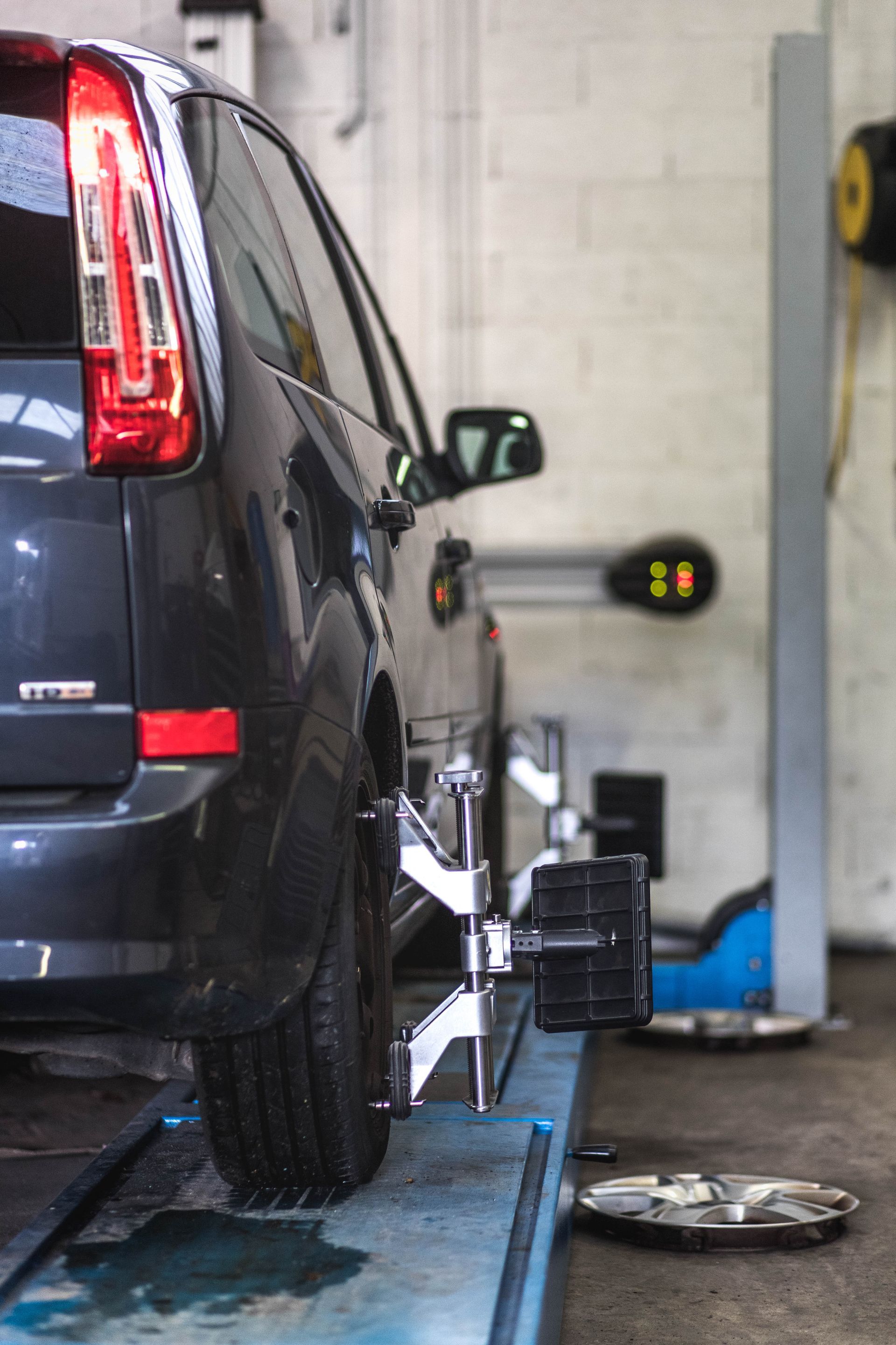 Voiture en cours de réglage d'alignement des roues dans un garage ; pneu arrière, monté sur une machine.