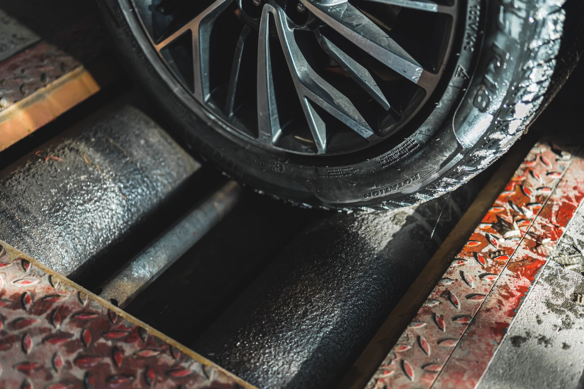 Pneu de voiture sur un dynamomètre, prêt à être testé, avec des surfaces métalliques.