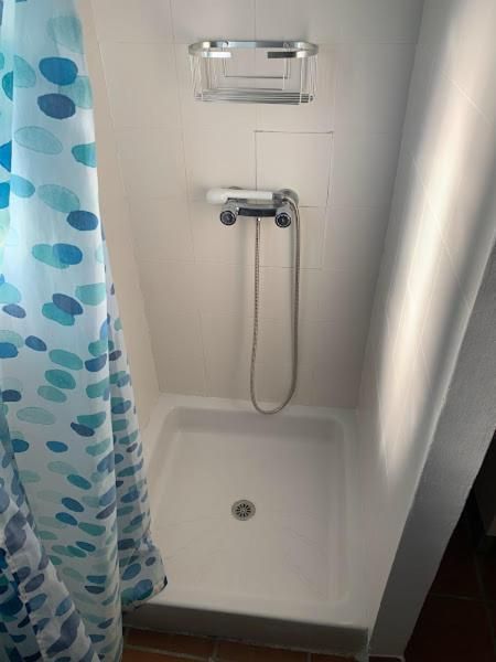 Cabina de ducha blanca en espacio en ángulo, con cortina de ducha.