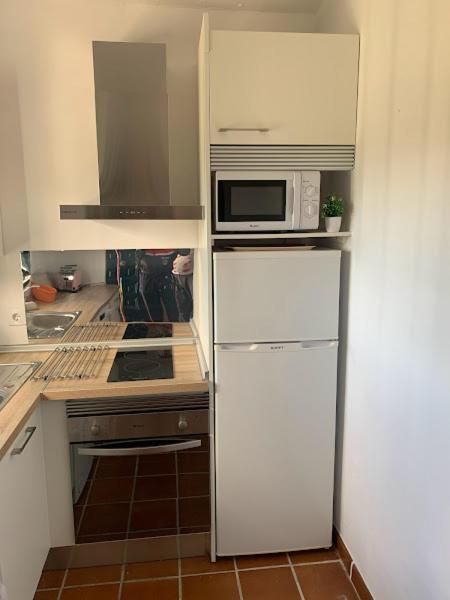 Cocina pequeña: refrigerador, microondas y gabinetes blancos; horno y estufa.