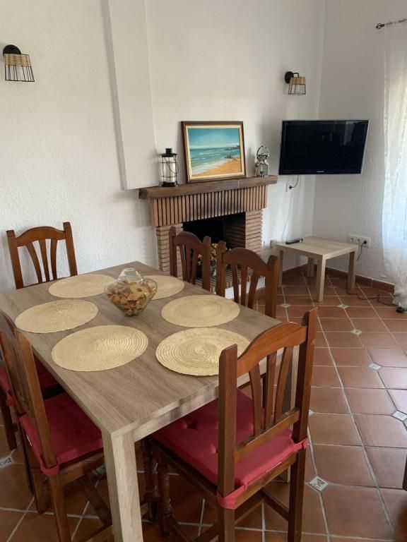 Comedor con mesa de madera, sillas, chimenea, TV y elementos decorativos.