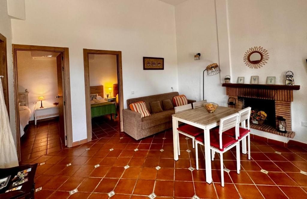 Sala de estar con chimenea, sofá, mesa de comedor y dos puertas abiertas.