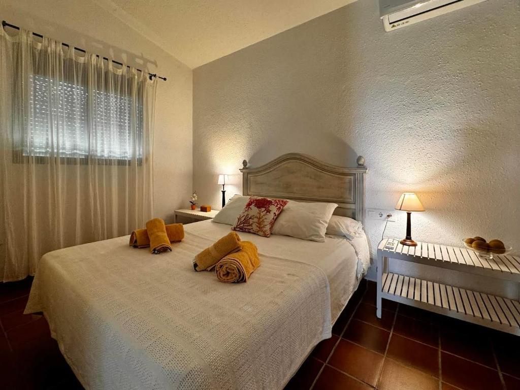 Dormitorio con cama de matrimonio, mesitas de noche, ventana con cortinas e iluminación cálida.