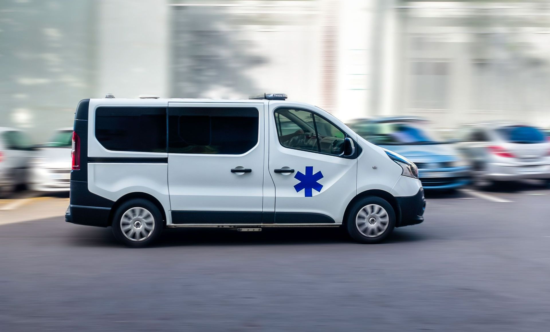 Une ambulance en train de rouler dans une ville avec des voitures en arrière-plan