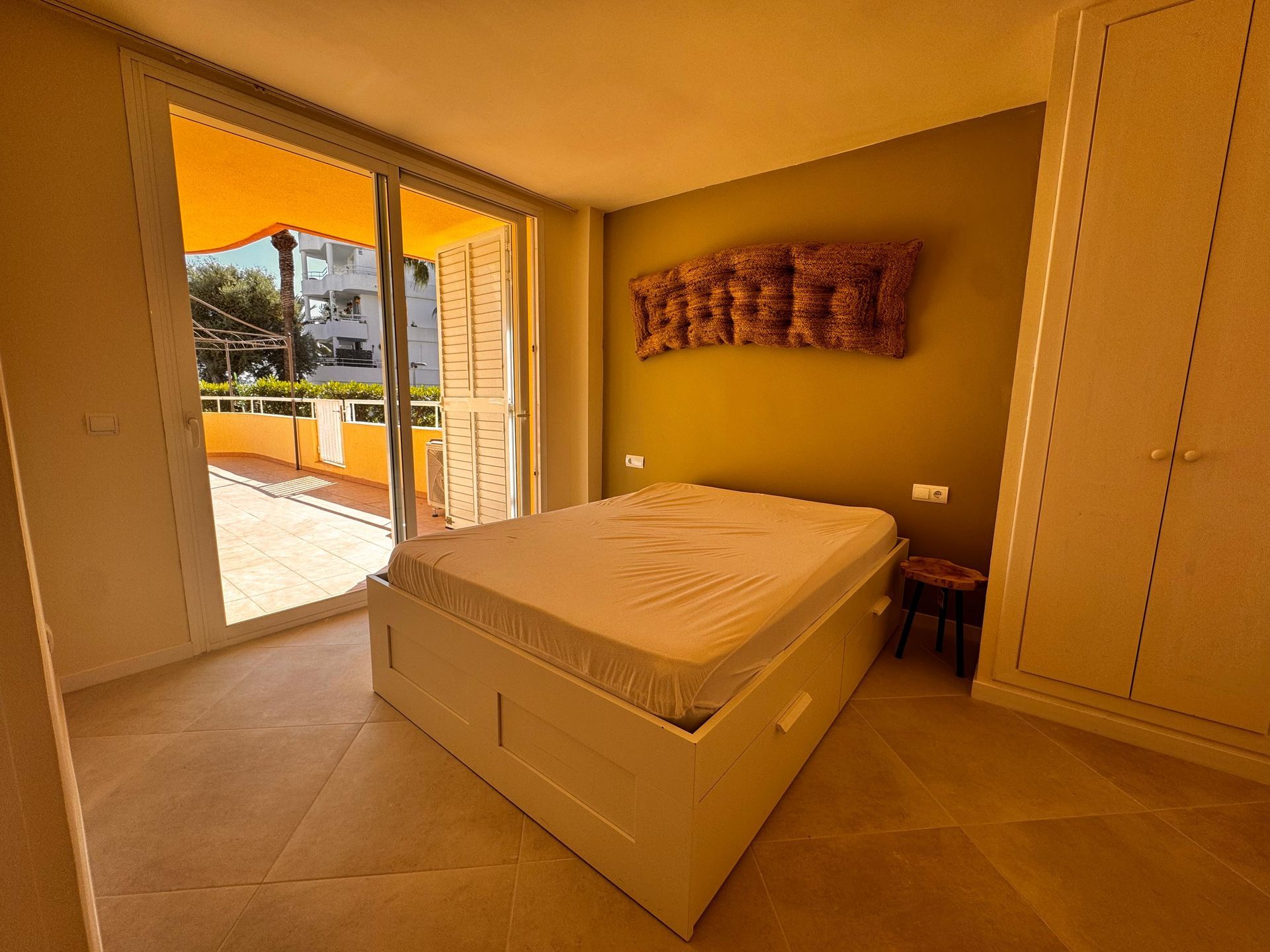 Dormitorio con cama, puertas corredizas a balcón, pared verde oliva, armario.