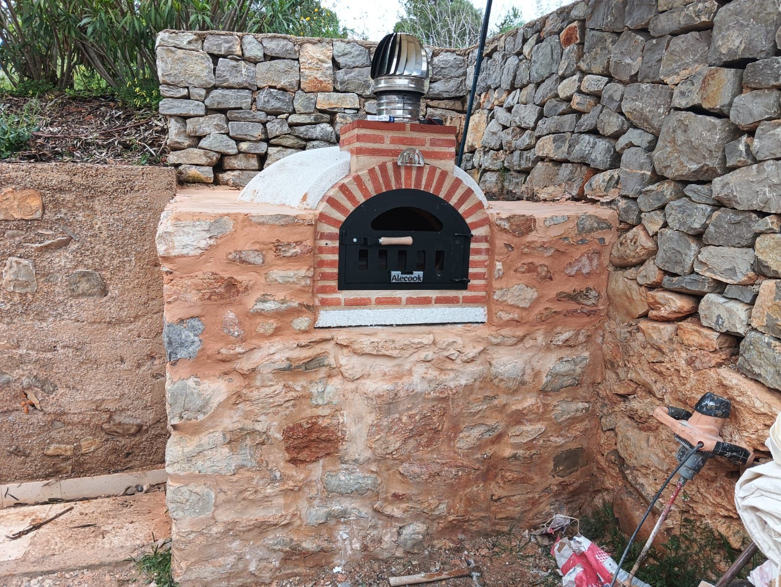Horno de ladrillo al aire libre con cerramiento de piedra.
