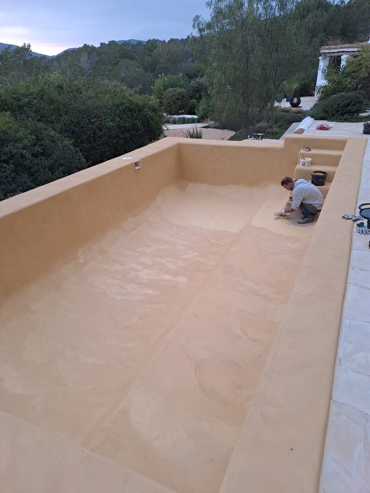 Hombre trabajando en una piscina vacía de color canela al aire libre.