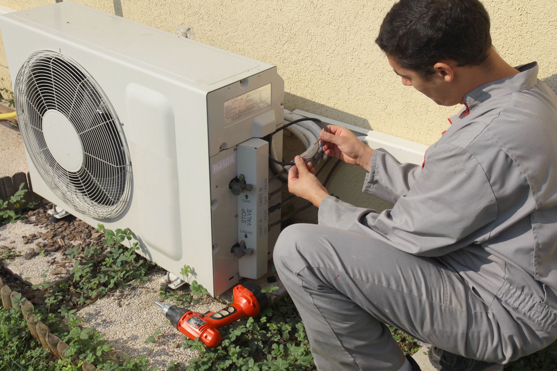 Un ouvrier répare une climatisation