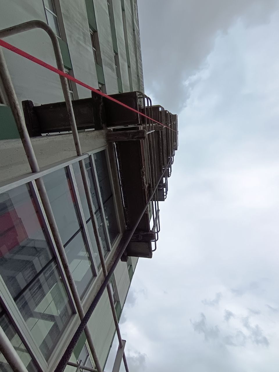 Un edificio alto con balcones visto desde abajo contra un cielo nublado.