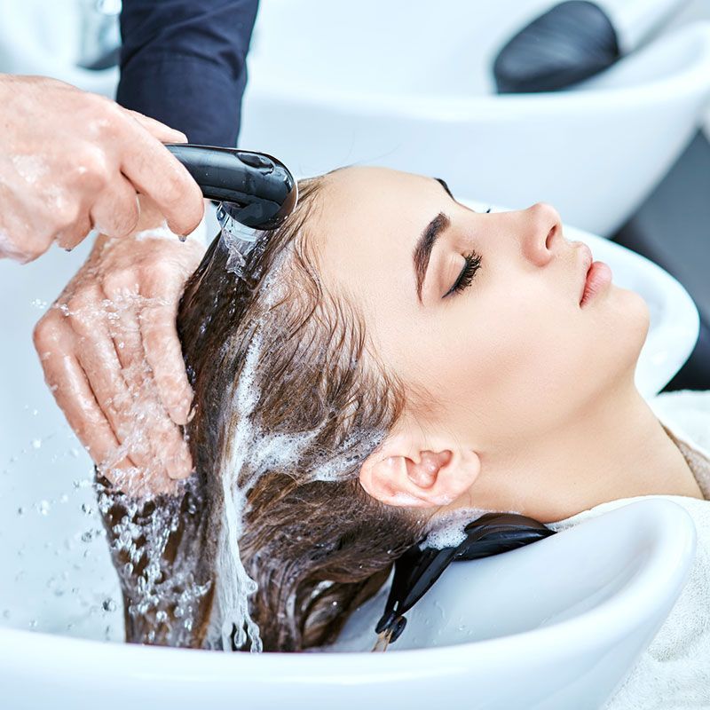 Einer Frau werden in einem Waschbecken in einem Salon die Haare gewaschen.