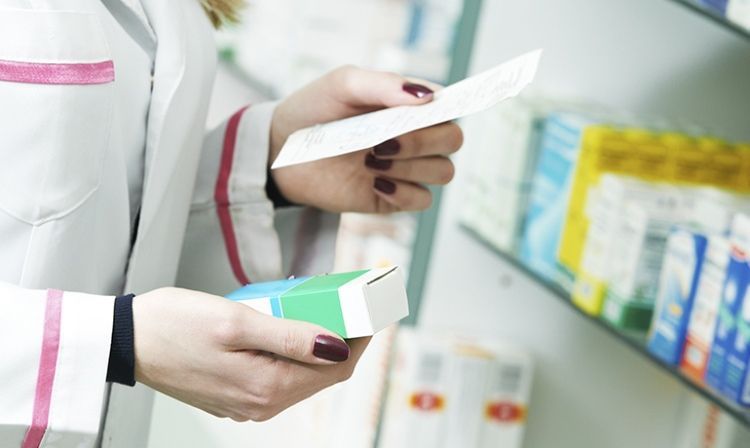 Mani di farmacista che mantengono scatola di farmaci