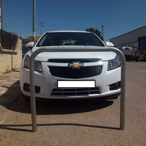 Un automóvil Chevrolet blanco está estacionado detrás de una barandilla de metal.