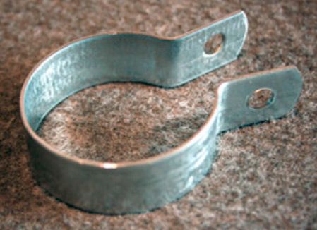 Una abrazadera de tubo de metal con un agujero en el medio está colocada sobre una alfombra.