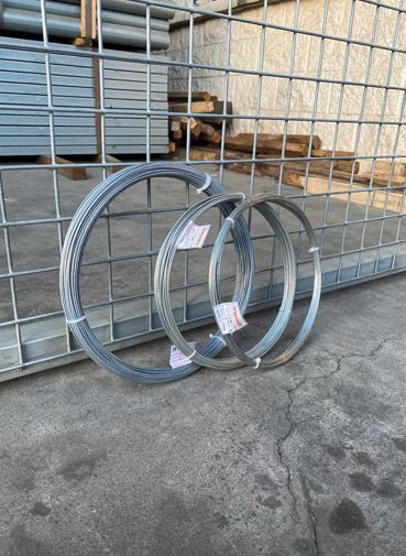 Tres rollos de alambre están en el suelo delante de una valla.
