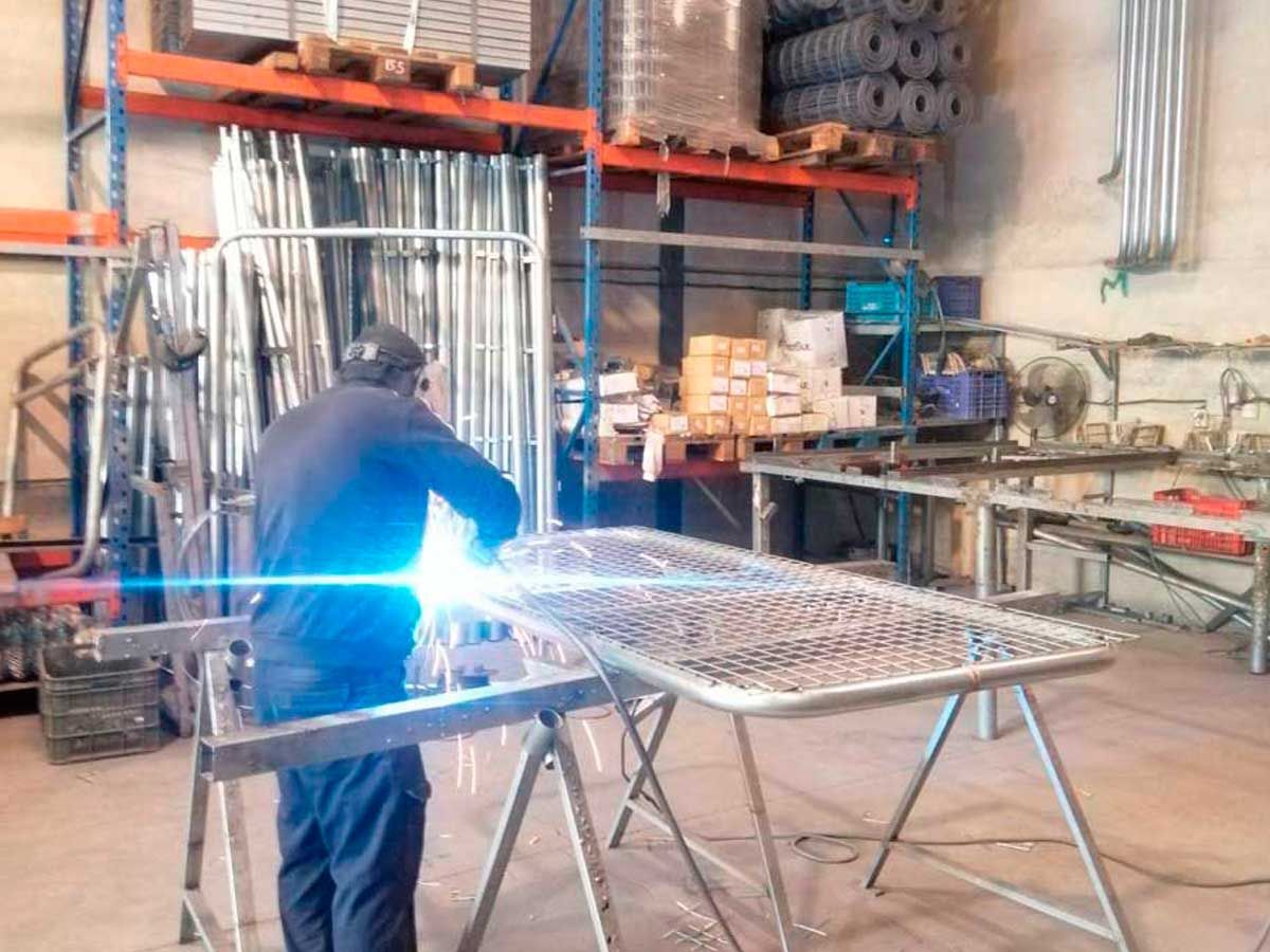 Un hombre está soldando una pieza de metal en un almacén.