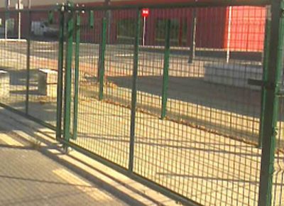 Una valla verde con un cartel rojo encima