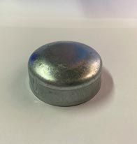 Una tapa de metal se encuentra encima de una superficie blanca.