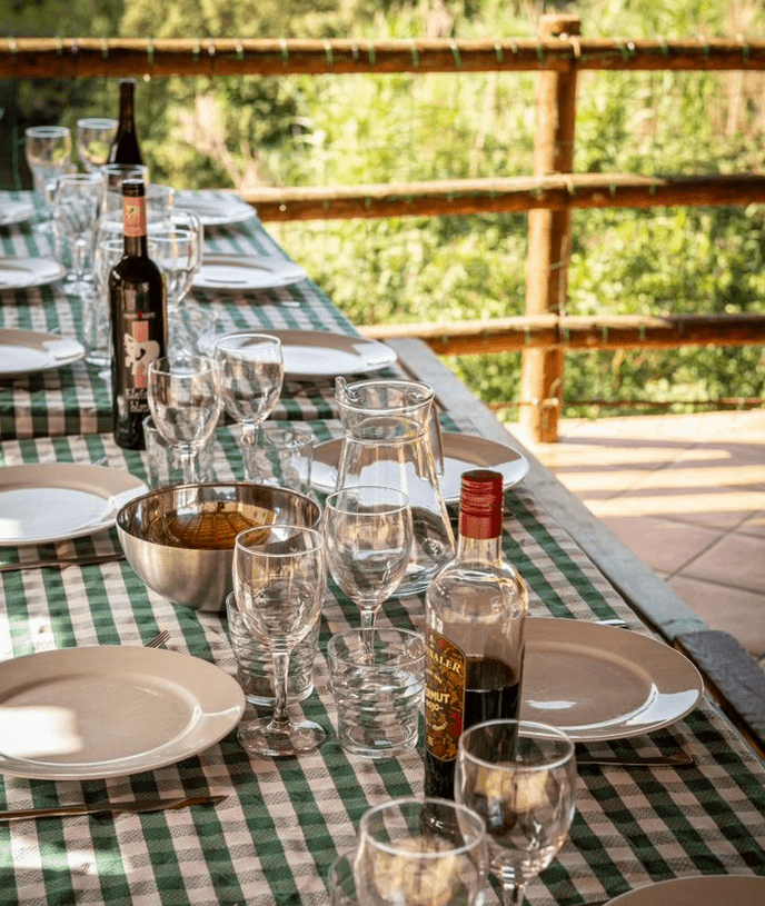 Una mesa larga con platos, vasos y botellas de vino sobre ella.
