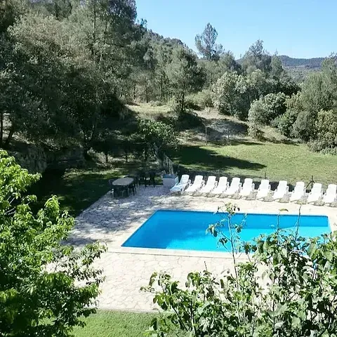 Una gran piscina rodeada de sillas y árboles.