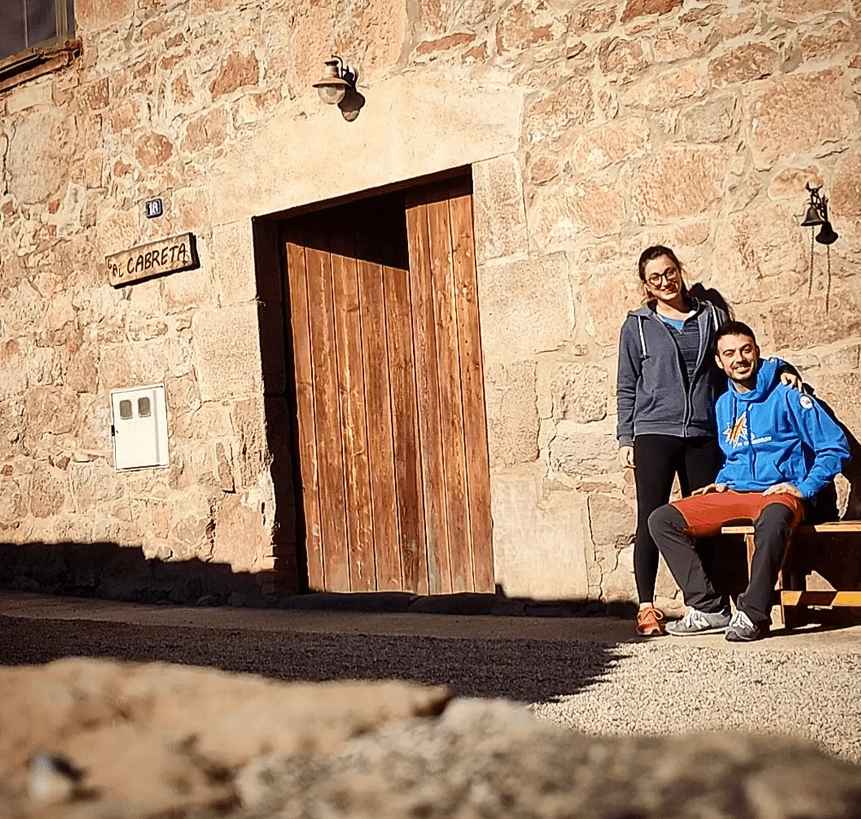 Dos personas posan para una foto frente a un edificio de piedra.
